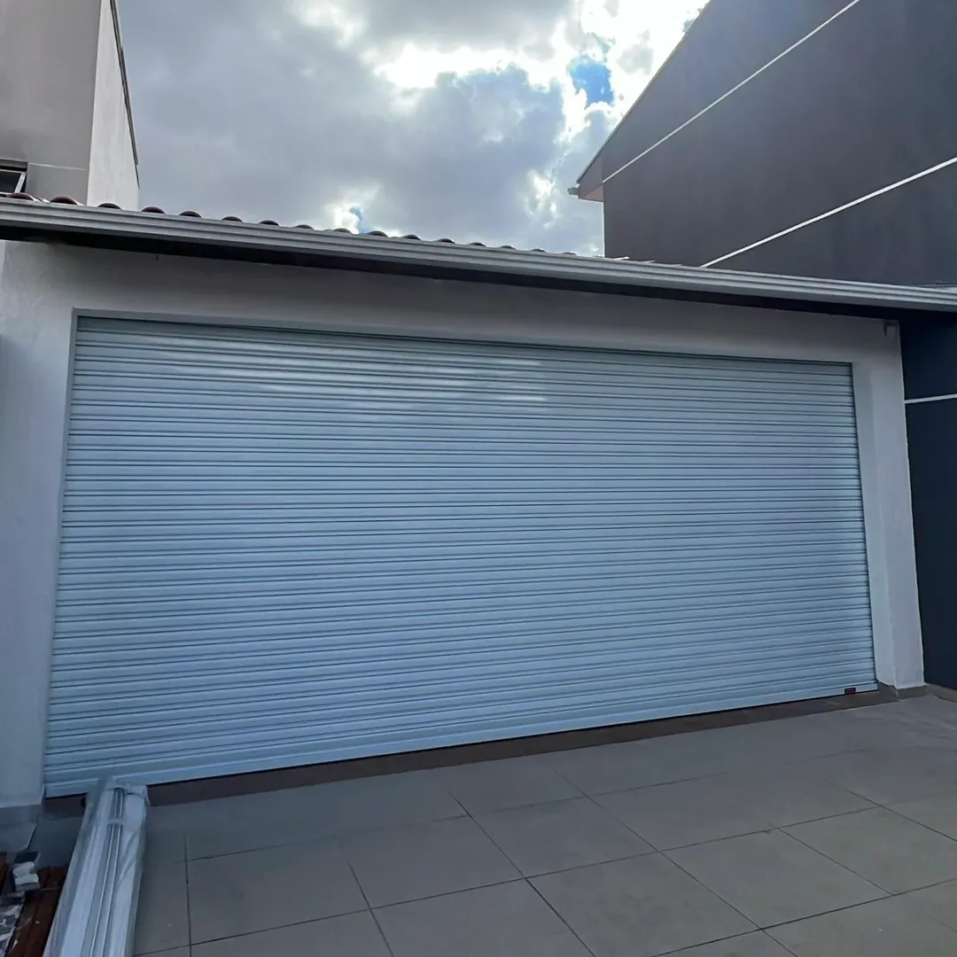 Porta de enrolar cinza instalada em garagem residencial